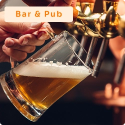 Pessoa enchendo copo de chope em torneira de bar, com espuma se formando, representando o serviço em bar ou pub.